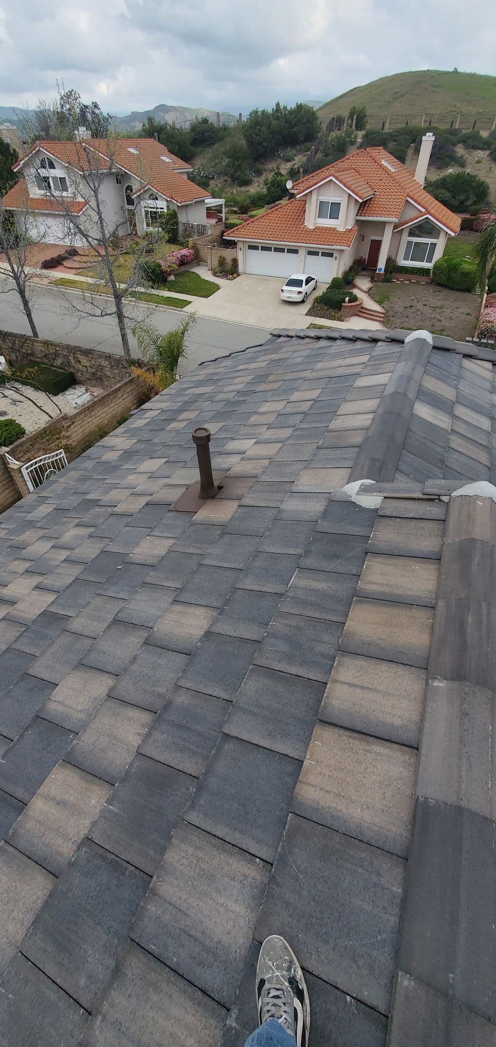 View from a rooftop showing shingles, chimney, and residential neighborhood below.