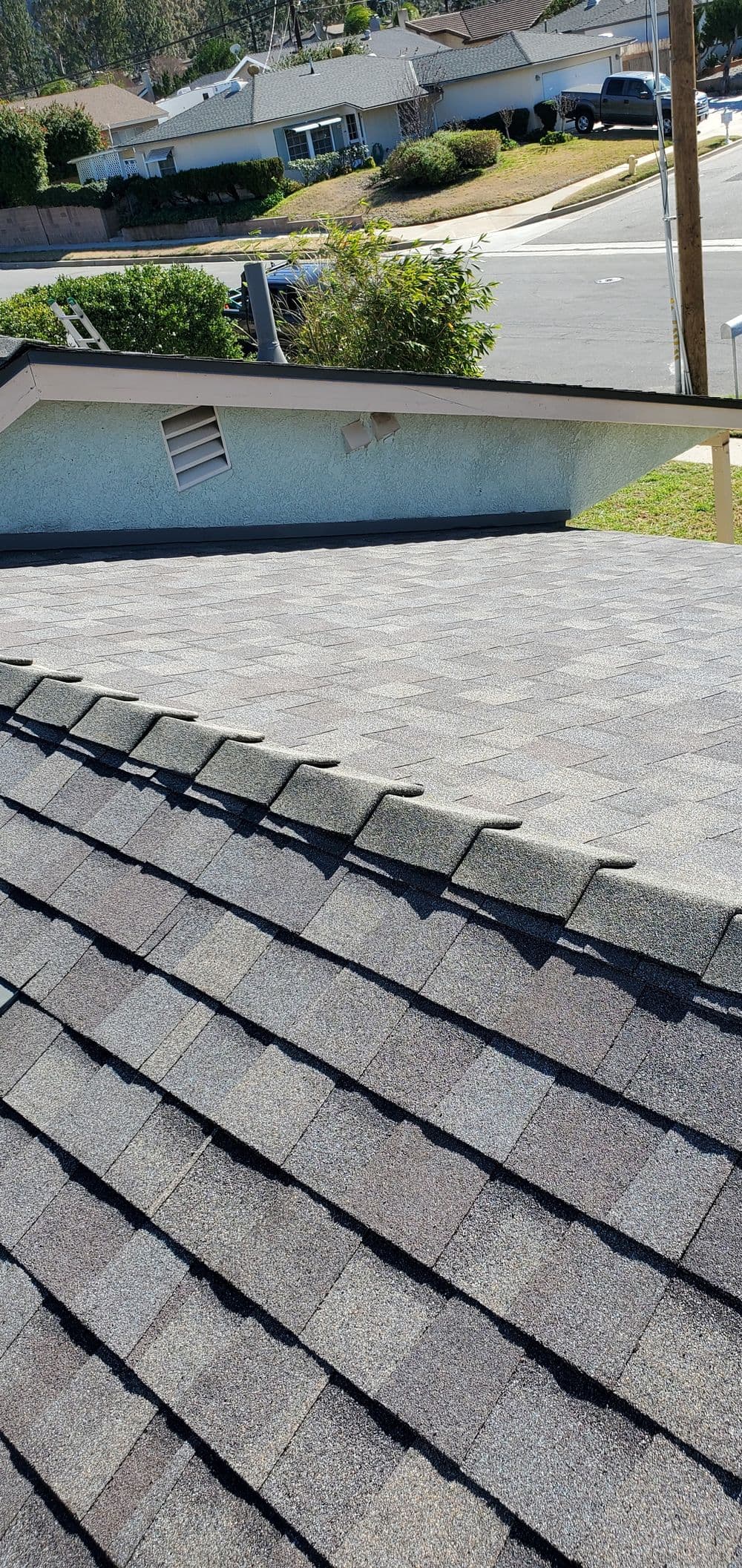 Aerial view of a residential roof with shingles, showing roof texture and surrounding neighborhood.